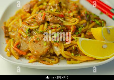 Nouilles aux œufs cuites à la main avec canard râpé dans une sauce à la prune, au gingembre, au Chili et à l'ail avec oignons, carottes, pak choi, châtaignes d'eau, o Banque D'Images