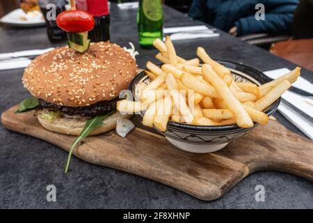 Hamburger servi avec un plat de frites présenté sur un plat en bois. Banque D'Images