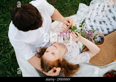 Une jeune fille aux cheveux rouges regarde amoureuse de son partenaire, tenant un cadeau de fleurs. Banque D'Images