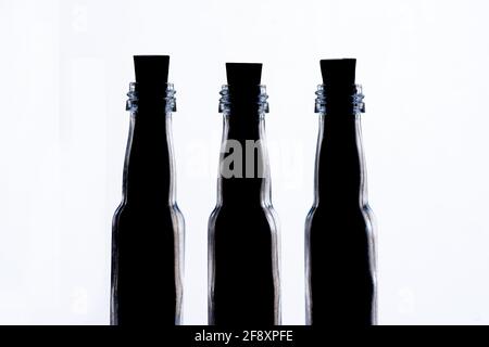 Trois quarts de prise de vue de trois petites bouteilles en verre rétroéclairées de suite. Les balises sont remplies de contenu vers le haut et scellées avec des bouchons en liège. Banque D'Images