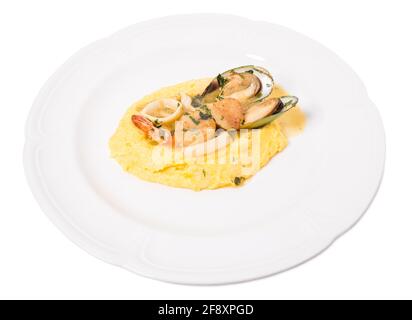 Délicieux pétoncles et moules cuits avec des rondelles de calmar sur une bouillie de maïs polenta. Isolé sur un fond blanc. Banque D'Images