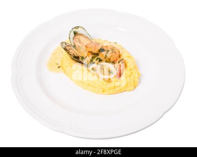 Délicieux pétoncles et moules cuits avec des rondelles de calmar sur une bouillie de maïs polenta. Isolé sur un fond blanc. Banque D'Images