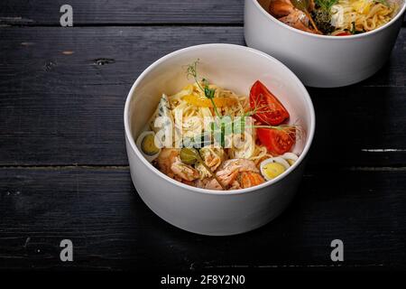 Pâtes au saumon. Plat méditerranéen appétissant : pâtes, saumon cuit au four, tomates, câpres et sauce au piment vert. Délicieux plats méditerranéens dans un bol blanc Banque D'Images