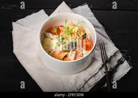 Pâtes au saumon. Plat méditerranéen : pâtes, saumon cuit, tomates, câpres, œuf de caille, fromage bleu et sauce au piment vert. Cuisine méditerranéenne dans un b blanc Banque D'Images