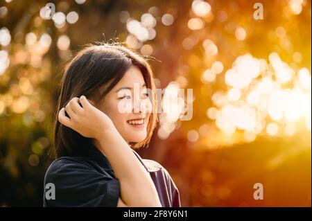 Asiatique mignon jeune fille innocente timide sourire bonheur moment avec nature soleil magnifique fond Banque D'Images