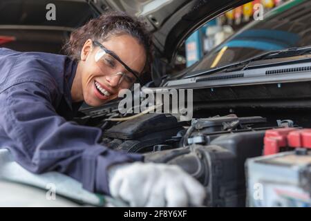 Femme travailleuse au centre de service automobile, femme en mécanique automobile travaille dans le garage technicien de service de voiture vérifier et réparer la voiture du client, inspecter la voiture Banque D'Images