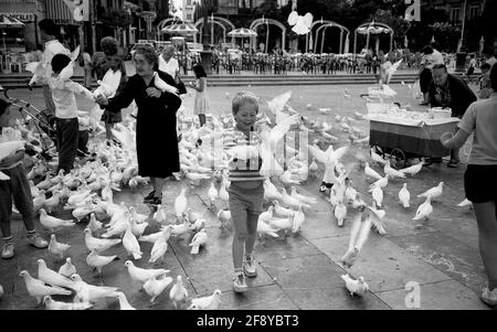 Valence Espagne 1987 vieille dame avec pigeons blancs colombes vendre semences d'oiseaux pour les enfants touristes Banque D'Images