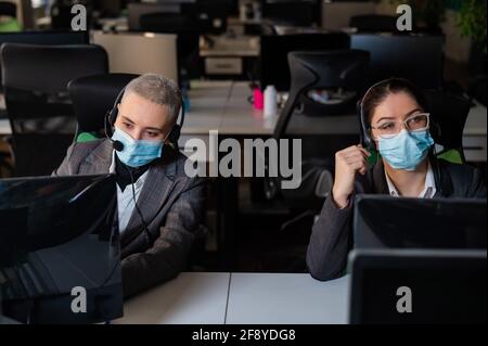 Deux femmes dans les masques médicaux travaillent dans le bureau. Opérateurs de centre d'appels féminins Banque D'Images