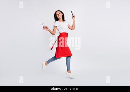 Photo pleine taille de profil optimiste brunette longue coiffeuse avec saut à la brosse, porter un t-shirt jean isolé sur fond gris Banque D'Images