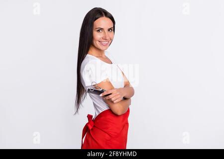 Photo de profil d'optimiste brunette longue coiffeuse avec brosse porter un tablier de t-shirt isolé sur fond gris Banque D'Images