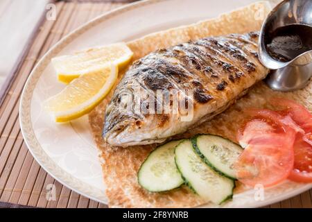 Poisson avec légumes rôtis dorada sur fond de bois Banque D'Images