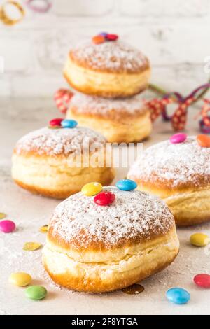 Beignets en poudre de sucre de Carnival, avec banderoles en papier, confetti et grains de chocolat sur fond blanc, vertical Banque D'Images