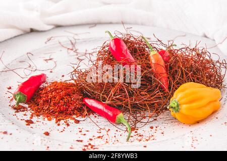 Gousses de piment, flocons et fils sur fond blanc Banque D'Images