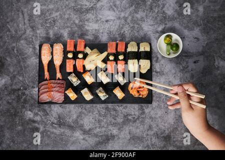 Vue de dessus de délicieux sushis servis sur un bois noir plaque avec baguettes Banque D'Images