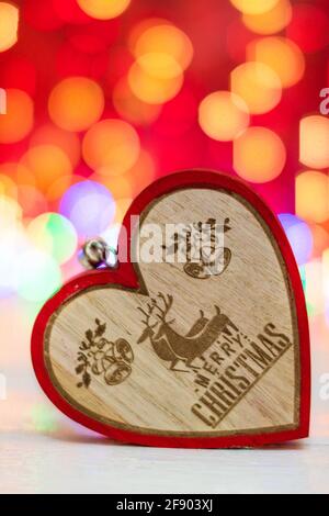 Ornement de Noël en forme de coeur en bois. Décorations de Noël sur fond rouge brouillé. Banque D'Images