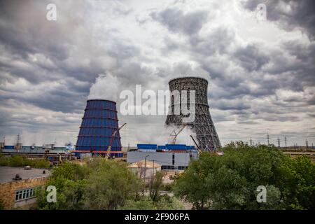 Centrale électrique thermique vue panoramique. Tours de refroidissement en arrière-plan. Arbres verts. Grues mobiles jaunes, ciel gris nuageux. Karaganda, Kazakhstan. Banque D'Images