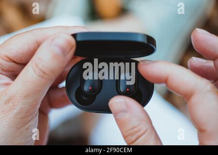 Gros plan d'une femme qui sort un écouteur sans fil son coffret de charge Banque D'Images