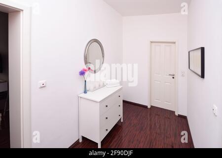 petit couloir derrière la porte avec placard blanc, miroir et fleurs Banque D'Images
