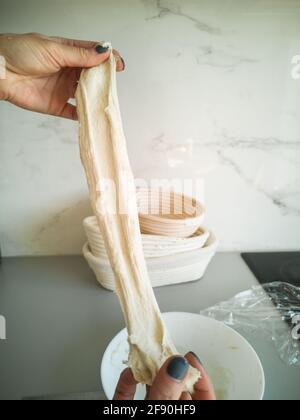 Les mains de la femme étirent la pâte sur le fond de panier de détuning. Gros plan Banque D'Images