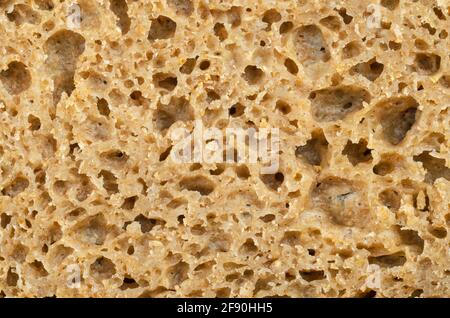 Surface d'un pain de seigle frais coupé, gros plan par le dessus. Pain au levain de couleur brune, mélange de farine de seigle, de levain et d'épices, cuit au four. Banque D'Images