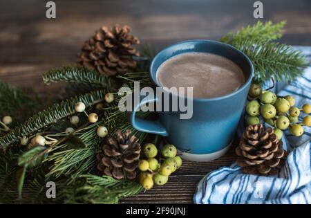 Tasse de chocolat chaud sur une table en bois avec des cônes de pin et des pâtes. Banque D'Images
