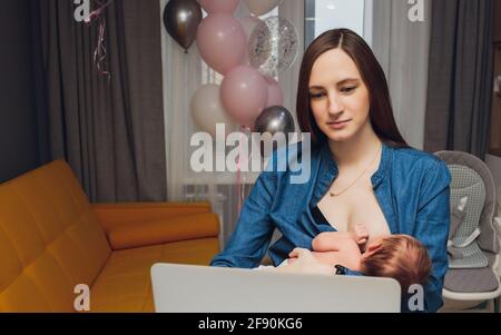 Belle jeune mère travaillant avec un ordinateur portable et allaitant, tenant et allaitant son nouveau-né à la maison. Maman - femme d'affaires nourrissant newb Banque D'Images