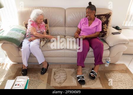 une femme de 93 ans joue à des cartes avec son aide médicale à domicile. La femme souffre de troubles cognitifs dégénératifs nécessitant une surveillance. Banque D'Images