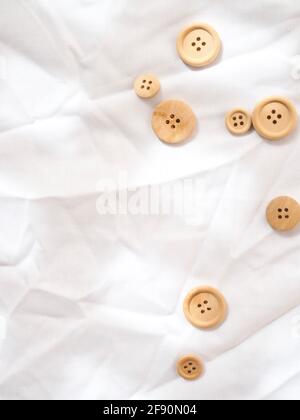 Boutons simples en bois sur fond blanc texturé et lumineux. Banque D'Images