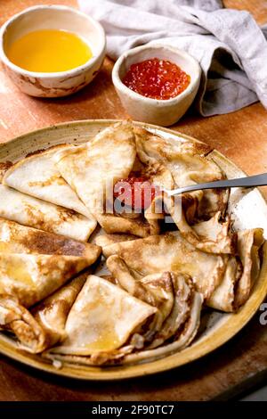 Crêpe de pansakes mince suzette servie avec du caviar rouge et du beurre fondu sur une plaque de céramique sur fond de pierre brune. Banque D'Images