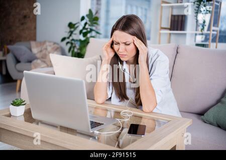 Photo de jeune malheureux contrarié humeur négative femme d'affaires ayant mal de tête souffrir de douleur après le travail assis canapé à la maison Banque D'Images