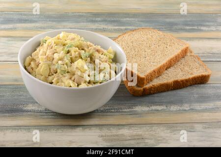 Salade de thon à base de germon avec pomme hachée et avocat en blanc bol à côté de deux tranches de cordon de blé entier Banque D'Images