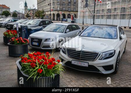 VARSOVIE. POLOGNE - AOÛT 2015 : voitures dans le parking du centre de Varsovie. Mercedes, Audi sont garés dans le centre-ville près des massifs fleuris avec des fleurs rouges. Photo de haute qualité Banque D'Images