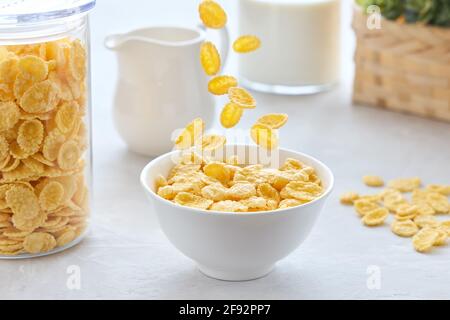 Petit-déjeuner traditionnel avec céréales et lait. Des cornflakes tombent dans un bol. Banque D'Images