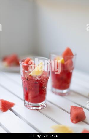 Smoothie d'été rafraîchissant à la pastèque fraîche avec citron et glace Dans un pot en verre sur un panneau en bois blanc orientation verticale de la photo Banque D'Images