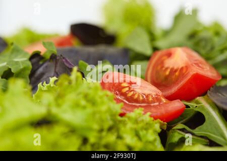 Mélange de salade fraîche de feuilles d'arugula, de basilic, de laitue agneaux et de tomates. Vue en gros plan. Banque D'Images