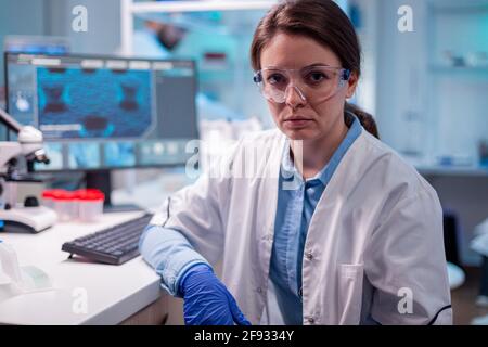 Femme médecin spécialiste de l'équipement de protection regardant la caméra avec des lunettes de sécurité. Chercheur en laboratoire de médecine de biologie travaillant avec des équipements technologiques professionnels pour le développement pharmaceutique. Banque D'Images