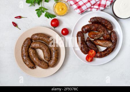 Saucisse de porc maison juteuse et saucisse végétarienne avec sarrasin sur des assiettes sur fond clair. Vue de dessus, plan d'appartement Banque D'Images