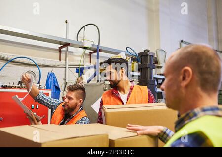 Les employés de l'entrepôt travaillent en équipe avec des boîtes en carton et des vérifications de liste de contrôle à l'arrivée livraison de marchandises Banque D'Images