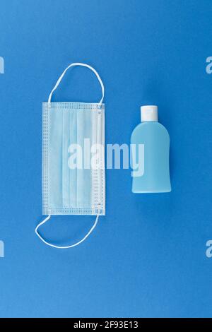 Vertical vue du dessus du flacon de gel désinfectant pour les mains et du masque médical pour le visage sur la bg bleue pour la mesure préventive du coronavirus, la prévention et la protection de la santé Banque D'Images