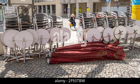 Munich, Allemagne. 16 avril 2021. Une femme passe devant des tables et des chaises assemblées dans un café du centre-ville. Credit: Peter Kneffel/dpa/Alay Live News Banque D'Images