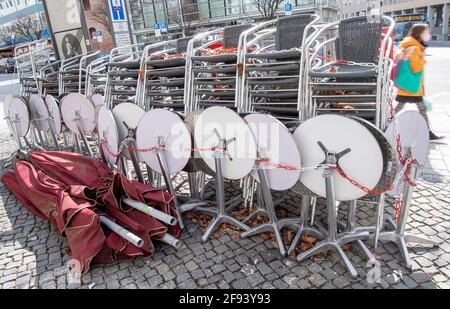 Munich, Allemagne. 16 avril 2021. Une femme passe devant des tables et des chaises assemblées dans un café du centre-ville. Credit: Peter Kneffel/dpa/Alay Live News Banque D'Images