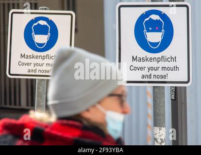 Munich, Allemagne. 16 avril 2021. Un passant portant une couverture de bouche et de nez passe devant des signes lisant « masques de macarie - couvrez votre bouche et votre nez ! » centre-ville. Credit: Peter Kneffel/dpa/Alay Live News Banque D'Images