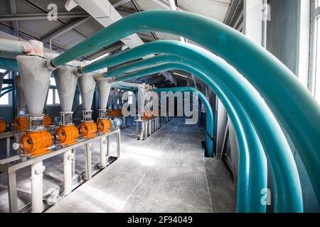 Région d'Aktobe, Kazakhstan - 06 mai 2012 : chaîne de production de farine de blé. Moteurs électriques avec trémies à cône et moulins à grain. Tuyaux en plastique bleu. Banque D'Images