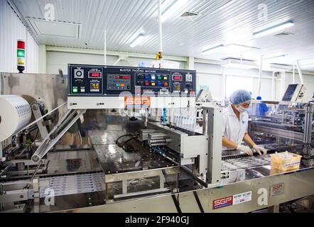 Atyrau, Kazakhstan. Usine de production de seringues médicales.jeune opérateur de femme Asain sur la ligne de production Banque D'Images