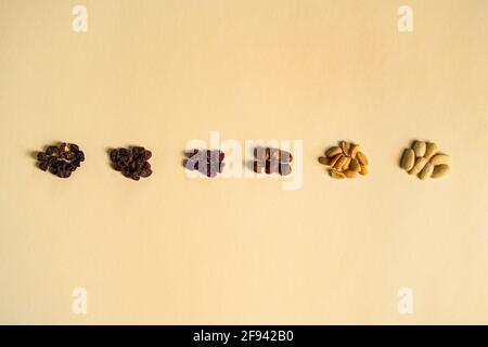 Mélange de noix et de fruits secs séparés par type et couleur sur fond jaune. Raisins secs, mûres séchées, noisettes, arachides et amandes. Banque D'Images