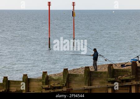 Un homme pêchant depuis une plage sur la côte sud de l'Angleterre. Banque D'Images