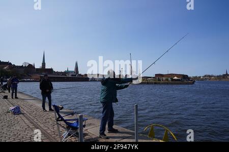 16 avril 2021, Schleswig-Holstein, Lübeck : les pêcheurs à la ligne pêchent dans la travée sous le plus beau soleil. Photo: Marcus Brandt/dpa Banque D'Images