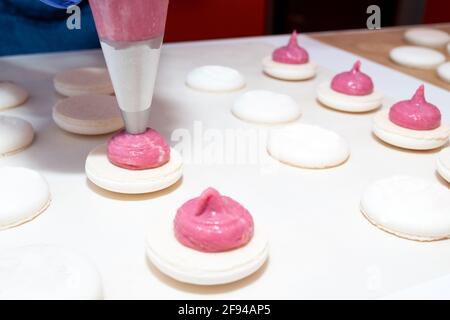 Le processus de fabrication du dessert macaroni. Application de la garniture à partir d'un sachet de pâtisserie. Banque D'Images