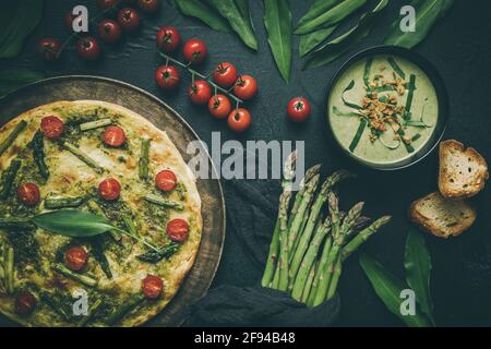 Tarte flambe maison avec asperges vertes et tomates et sauvage soupe à l'ail sur fond sombre Banque D'Images