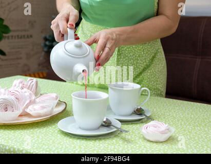 Dans une tasse blanche, versez le thé pour une fête de thé avec des guimauves. Mise au point sélective. Banque D'Images